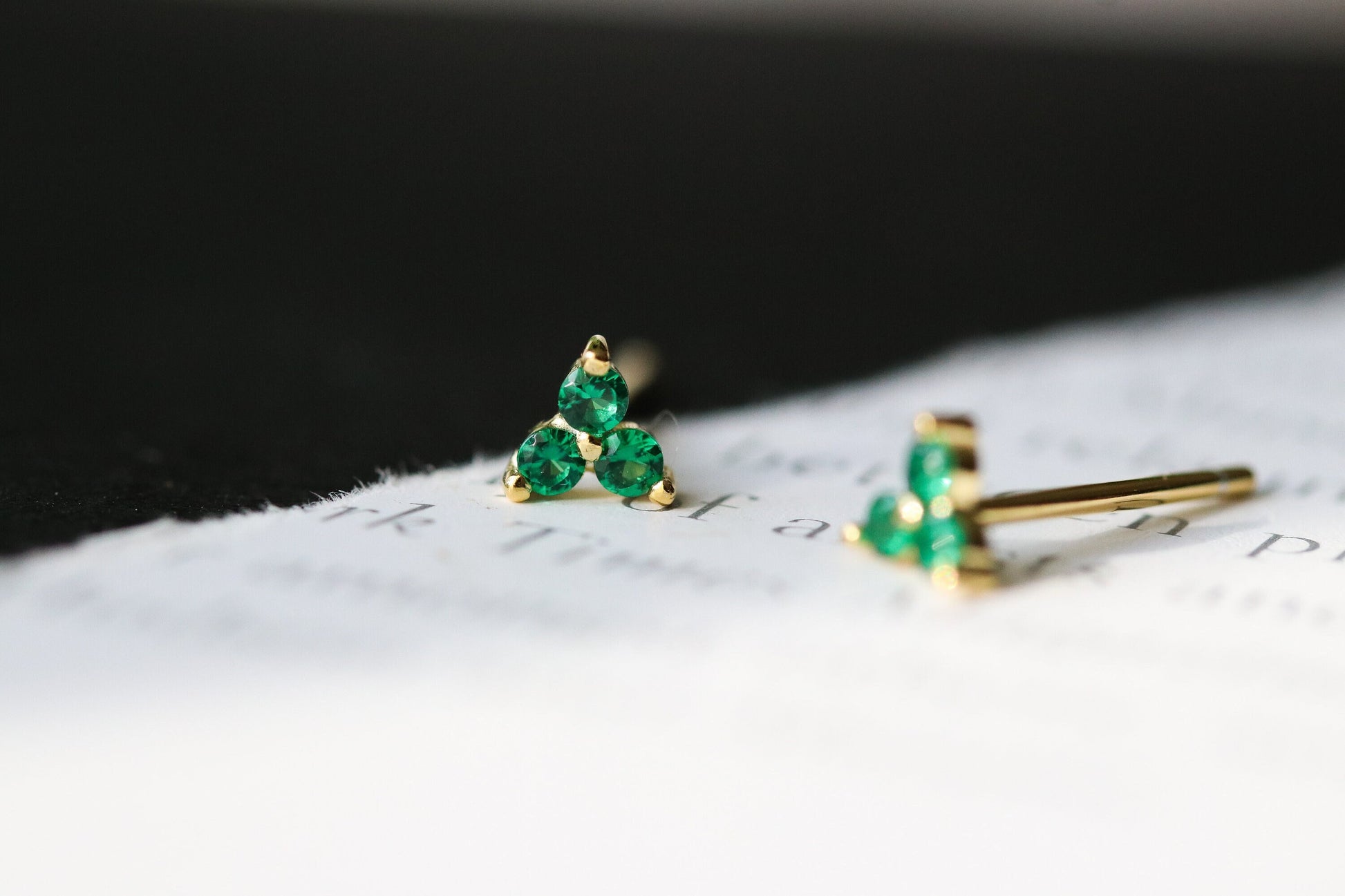 Shan&Co's Gold Vermeil CZ Emerald Shamrock Stud Earrings featuring a crystal emerald in a shamrock design, paired with Emerald Three Dot Earrings and Dainty Gold Trinity Leaf Earrings, blending elegance with nature-inspired charm in high-quality gold vermeil.