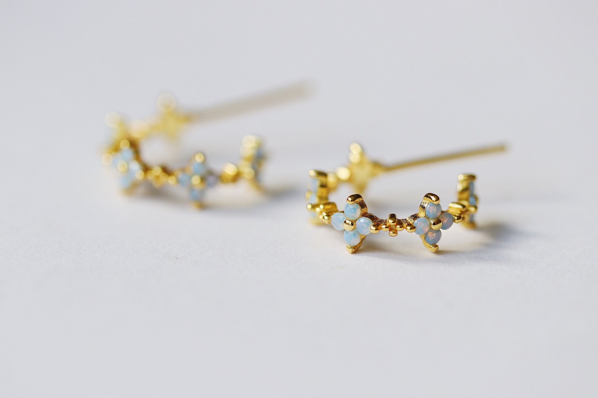 A pair of dainty hoop earrings featuring a delicate opal flower design and a four-leaf clover motif. Made from Sterling Silver/Gold Vermeil, these vintage-inspired earrings offer a charming, minimalist style. The opal adds a subtle pop of color, making them perfect for everyday wear or special occasions. The four-leaf clover design symbolizes good luck, making these floral hoops a meaningful and stylish accessory