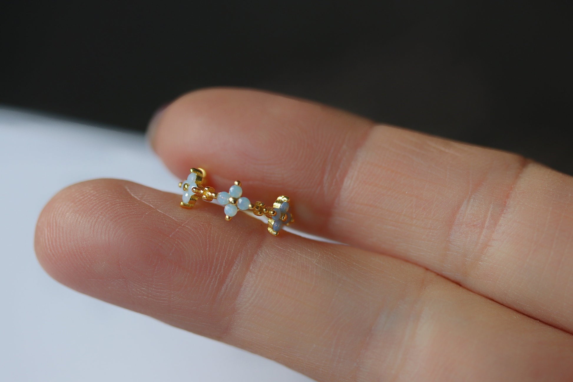 A pair of dainty hoop earrings featuring a delicate opal flower design and a four-leaf clover motif. Made from Sterling Silver/Gold Vermeil, these vintage-inspired earrings offer a charming, minimalist style. The opal adds a subtle pop of color, making them perfect for everyday wear or special occasions. The four-leaf clover design symbolizes good luck, making these floral hoops a meaningful and stylish accessory