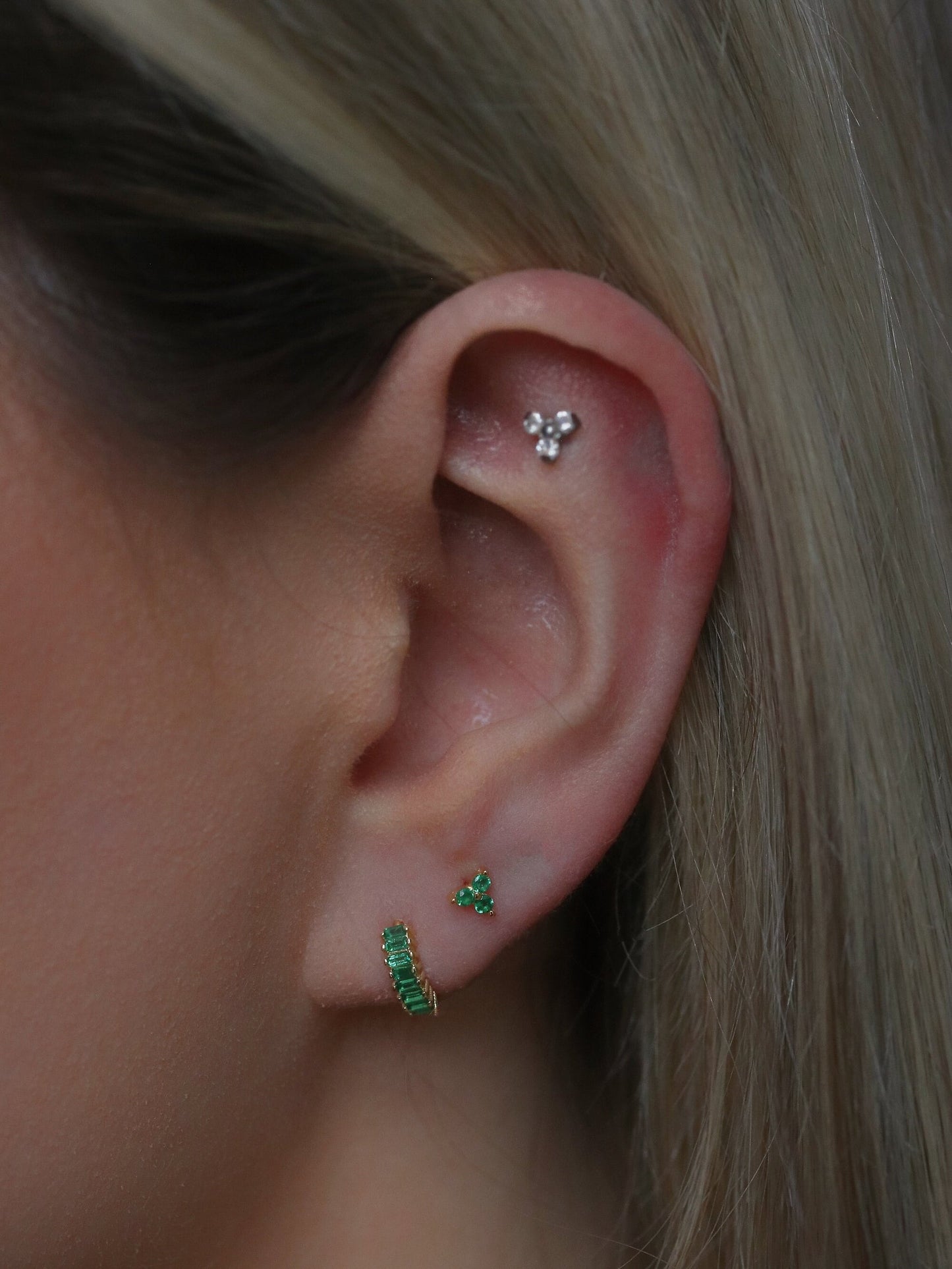 Shan&Co's Gold Vermeil CZ Emerald Shamrock Stud Earrings featuring a crystal emerald in a shamrock design, paired with Emerald Three Dot Earrings and Dainty Gold Trinity Leaf Earrings, blending elegance with nature-inspired charm in high-quality gold vermeil.