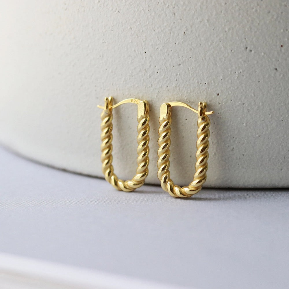 Shan&Co's Sterling Silver and Gold Twisted Oval Hoops Earrings featuring a beautifully crafted twisted design that combines sterling silver and gold for a sophisticated two-tone effect, perfect for adding elegance to any outfit.