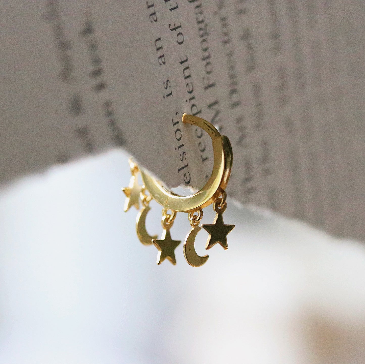 Shan&Co's Gold/Silver Star and Moon Huggies Earrings with delicate star and crescent moon dangle charms, crafted in high-quality gold or silver, perfect for adding a celestial touch to any outfit.