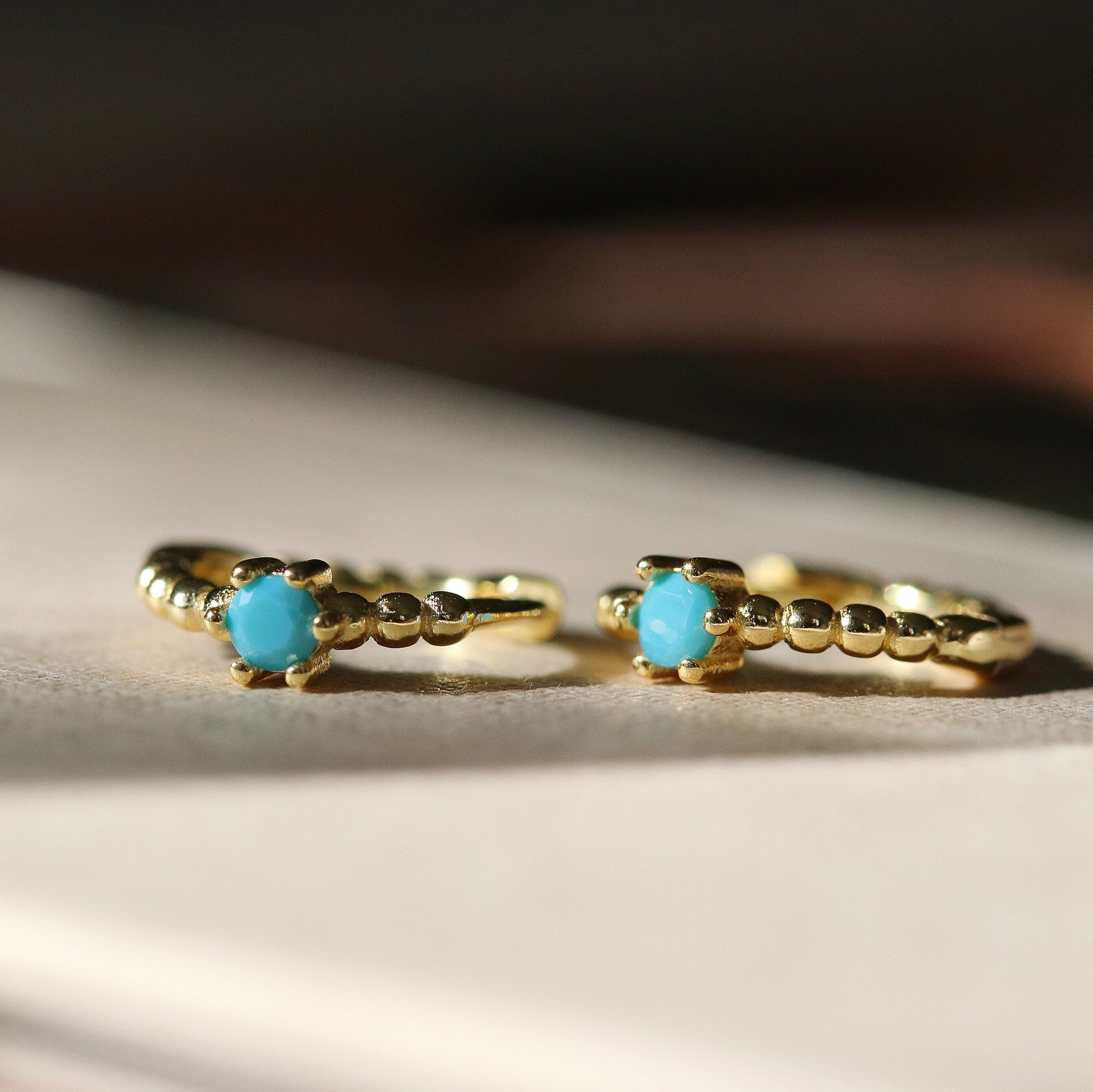 Shan&Co's Gold Turquoise Solitaire Hoop Earrings featuring a vibrant turquoise stone set in high-quality gold vermeil, designed as small huggies for a chic and elegant look.