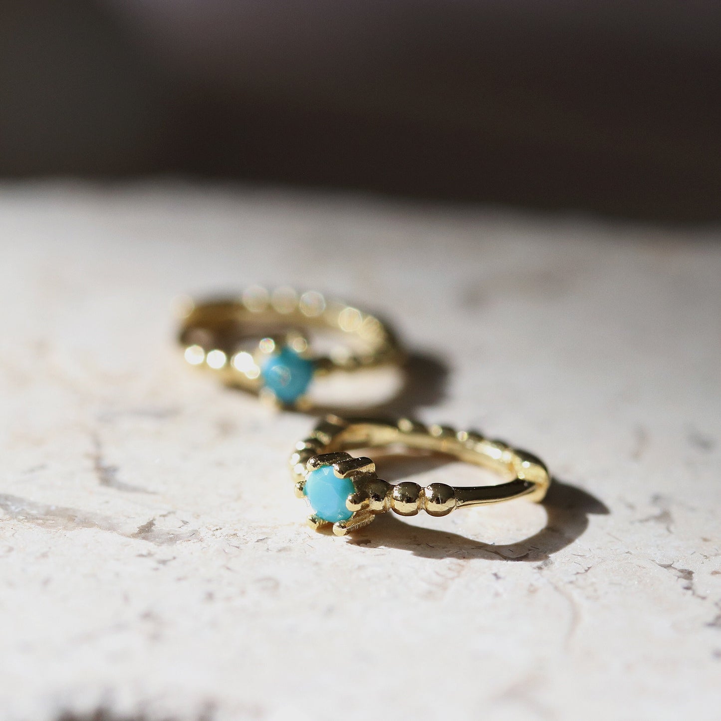 Shan&Co's Gold Turquoise Solitaire Hoop Earrings featuring a vibrant turquoise stone set in high-quality gold vermeil, designed as small huggies for a chic and elegant look.