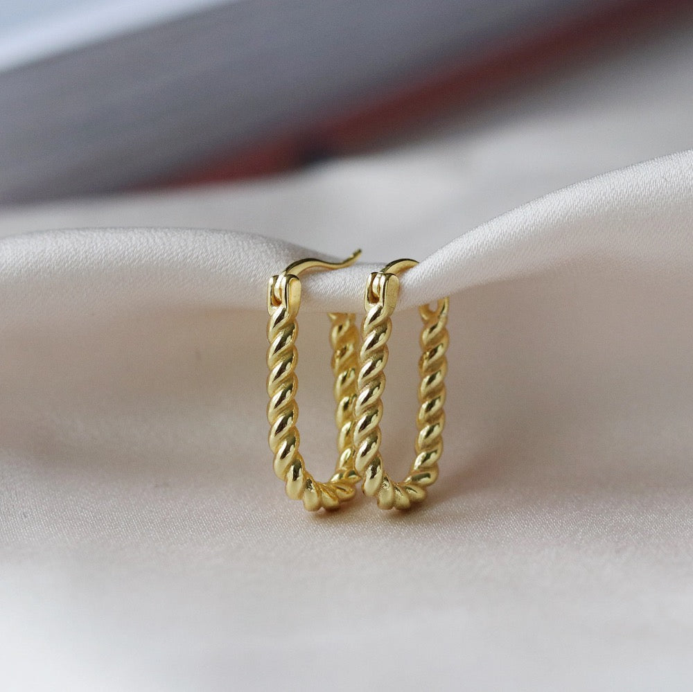 Shan&Co's Sterling Silver and Gold Twisted Oval Hoops Earrings featuring a beautifully crafted twisted design that combines sterling silver and gold for a sophisticated two-tone effect, perfect for adding elegance to any outfit.