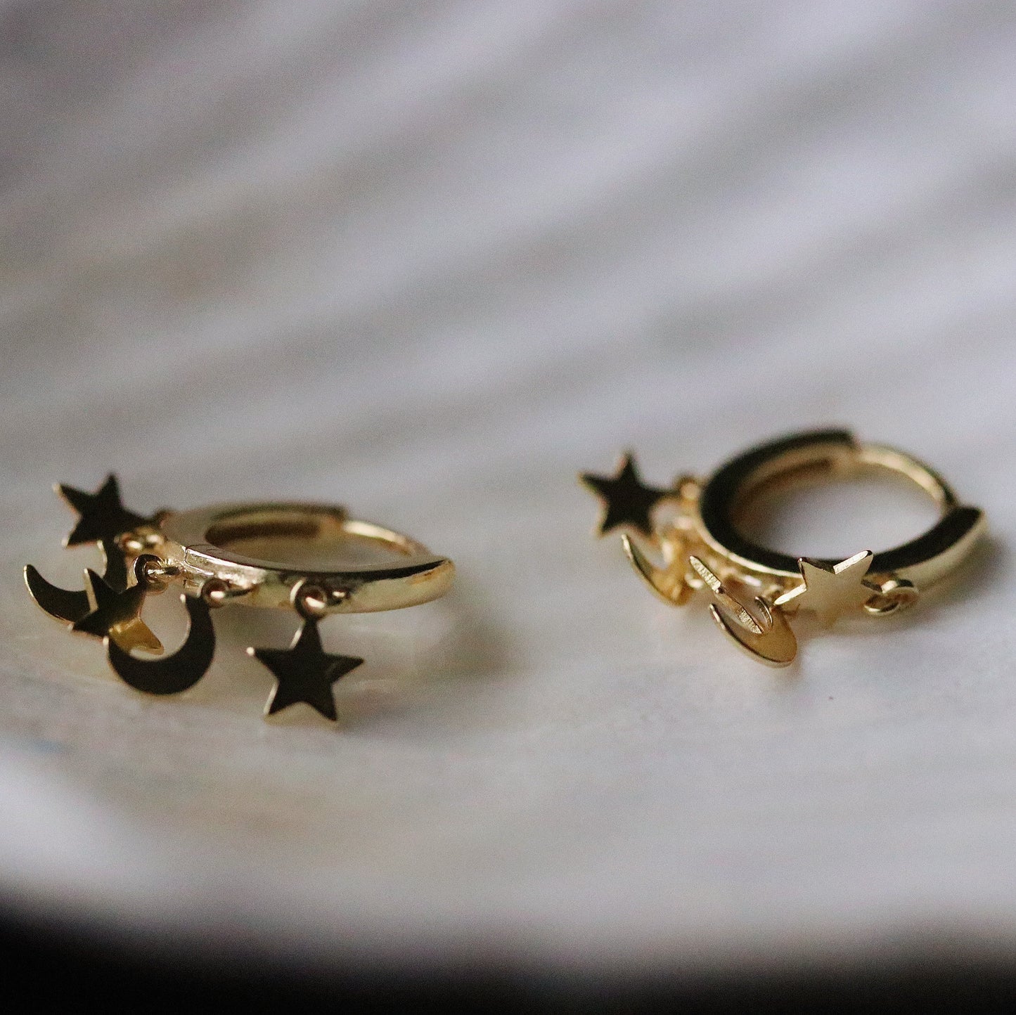 Shan&Co's Gold/Silver Star and Moon Huggies Earrings with delicate star and crescent moon dangle charms, crafted in high-quality gold or silver, perfect for adding a celestial touch to any outfit.