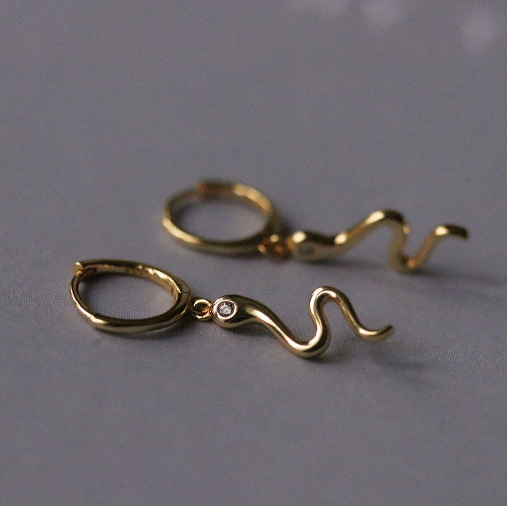 Sterling Silver/Gold Vermeil Snake Dangle Hoop Earrings featuring intricately detailed snake charms, adding a bold and elegant touch. Perfect for statement fashion.






