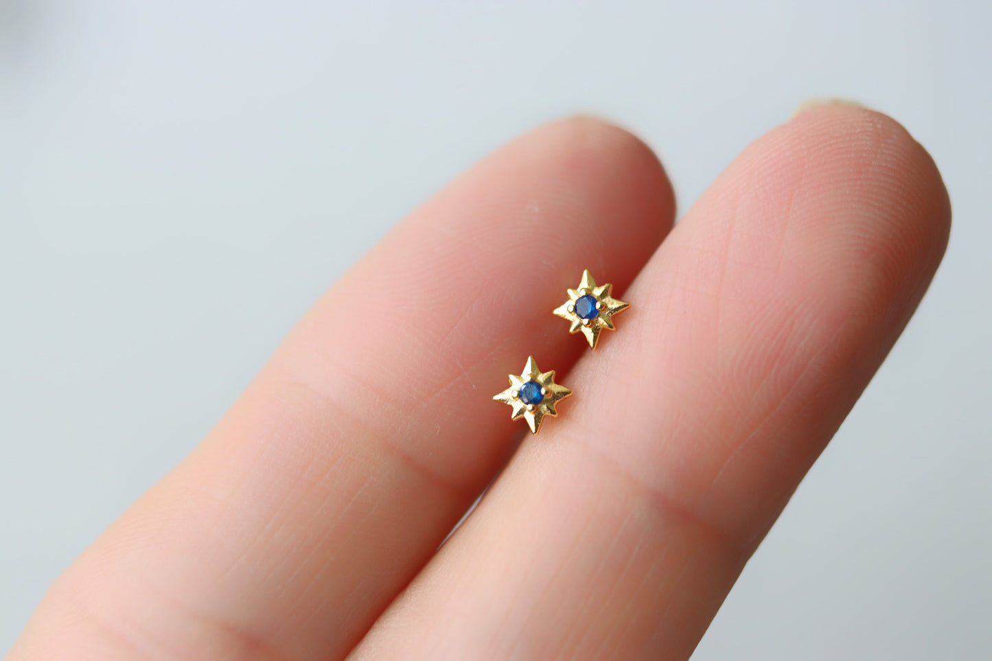 Shan&Co's Gold Starburst Screw Navy Earrings featuring a radiant starburst design with vibrant navy accents, paired with Star Barbell Earrings for a modern celestial look, crafted in high-quality gold.