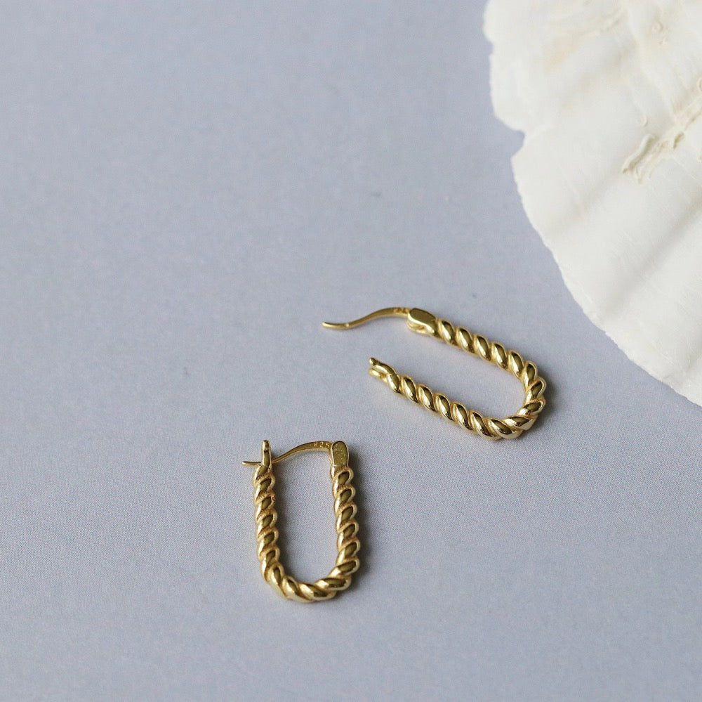 Shan&Co's Sterling Silver and Gold Twisted Oval Hoops Earrings featuring a beautifully crafted twisted design that combines sterling silver and gold for a sophisticated two-tone effect, perfect for adding elegance to any outfit.