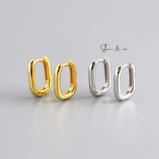 Shan&Co's Gold Rectangle Hoops Earrings with a bold rectangular design and Oval Curved Huggies offering a snug fit, both crafted from high-quality gold for a modern and sophisticated look.