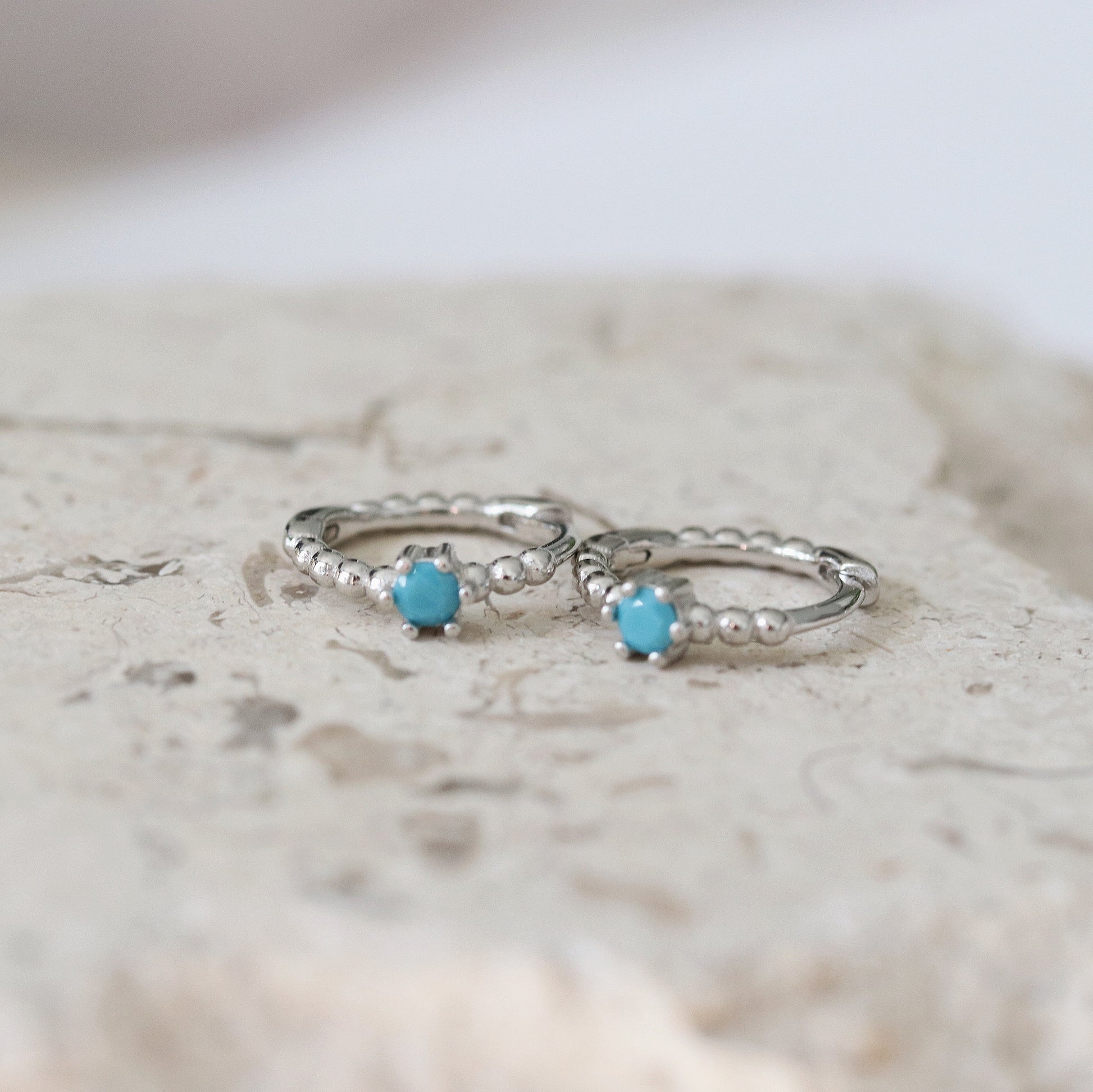 Shan&Co's Sliver Turquoise Solitaire Hoop Earrings featuring a vibrant turquoise stone set in high-quality gold vermeil, designed as small huggies for a chic and elegant look.