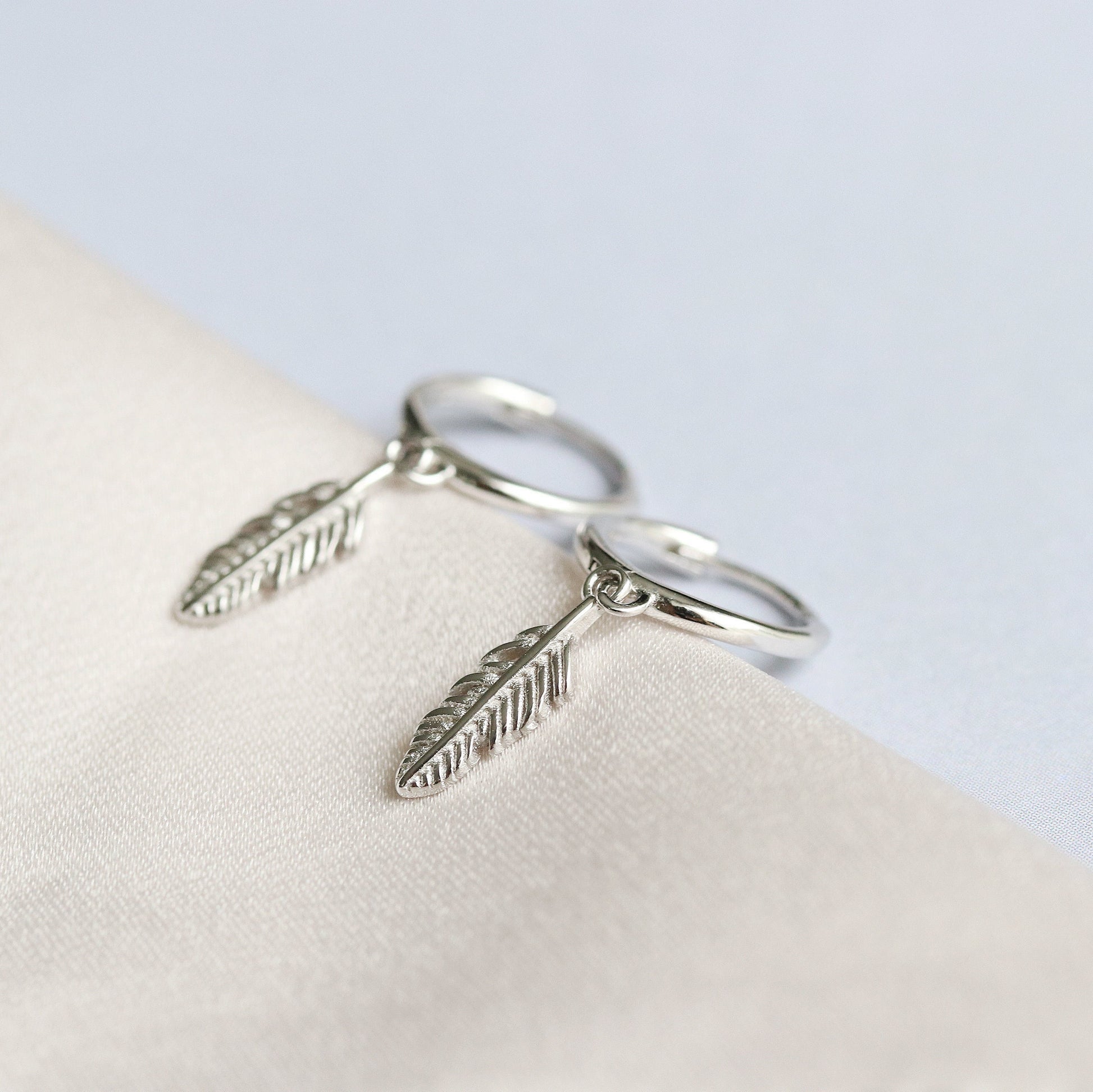 Shan&Co's Sterling Silver Feather Hoop Earrings featuring delicate feather charms, crafted from high-quality sterling silver, perfect for adding a light, bohemian touch to any outfit.