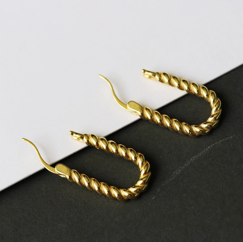 Shan&Co's Sterling Silver and Gold Twisted Oval Hoops Earrings featuring a beautifully crafted twisted design that combines sterling silver and gold for a sophisticated two-tone effect, perfect for adding elegance to any outfit.